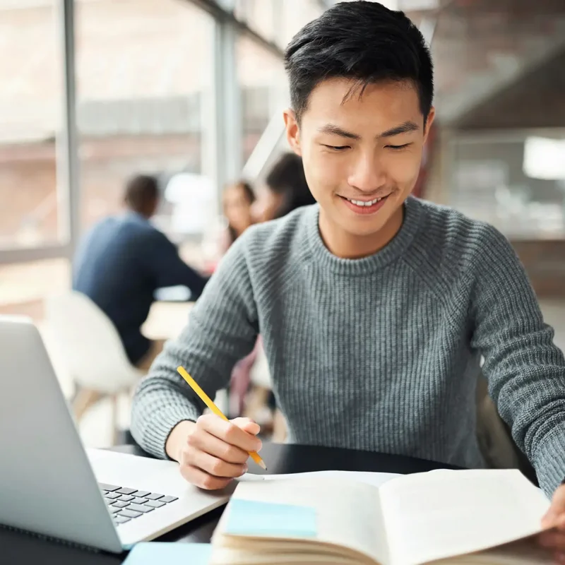 Asian man, laptop and notebook in education, learning or study on college, university or Japanese school campus. Smile, happy and graduate for law student with technology and legal scholarship books